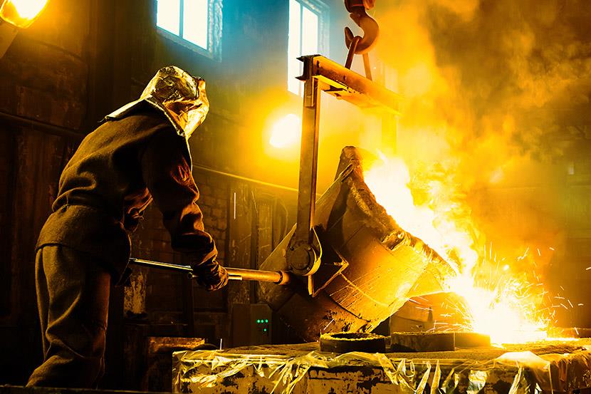 worker pouring molten metal into crucibles