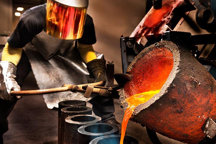 worker pouring molten steel into crucibles in a foundry