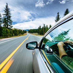 An image of an automobile driving down a country road.