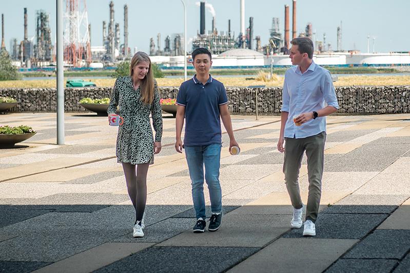 three people walking down a path holding coffee cups