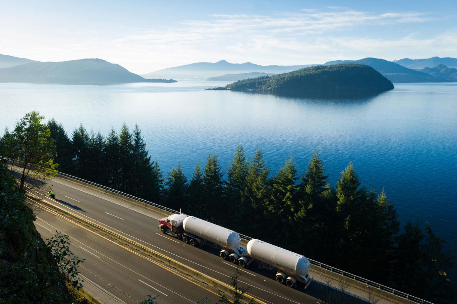 18 wheel truck carrying large tanks driving by a lake