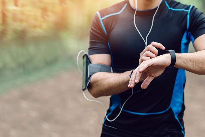 man in black running attire and wearing arm band with smartphone checking watch