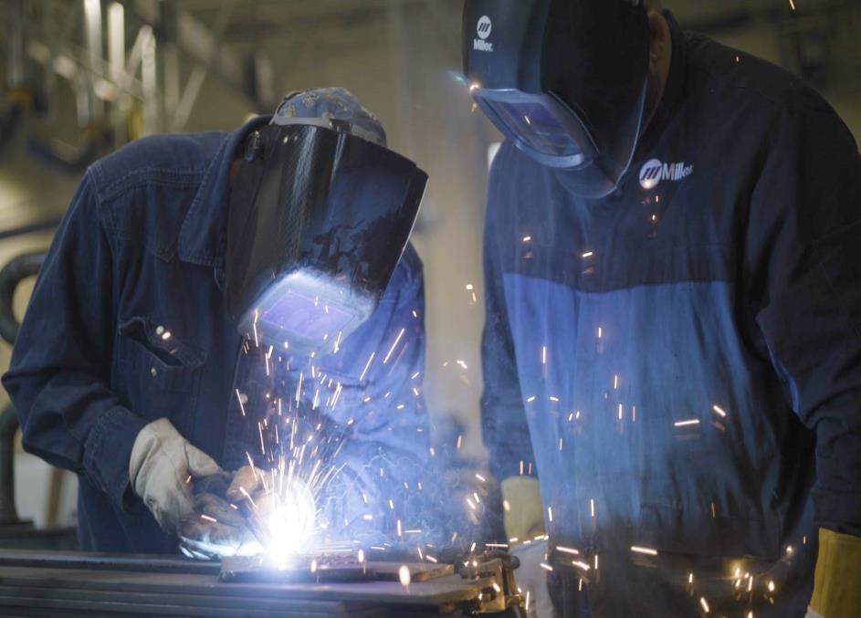 Two people in welding masks working on a piece