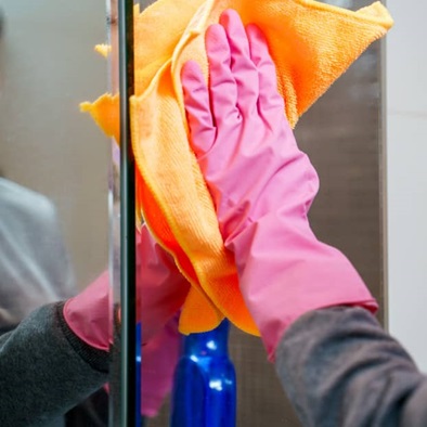 Gloved hand wiping glass with cloth