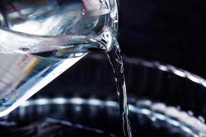 water being poured out of one glass container into another 